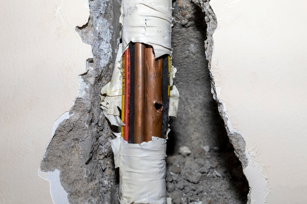 Damaged,Copper,Pipe,In,A,Wall,Surrounded,By,Various,Wires